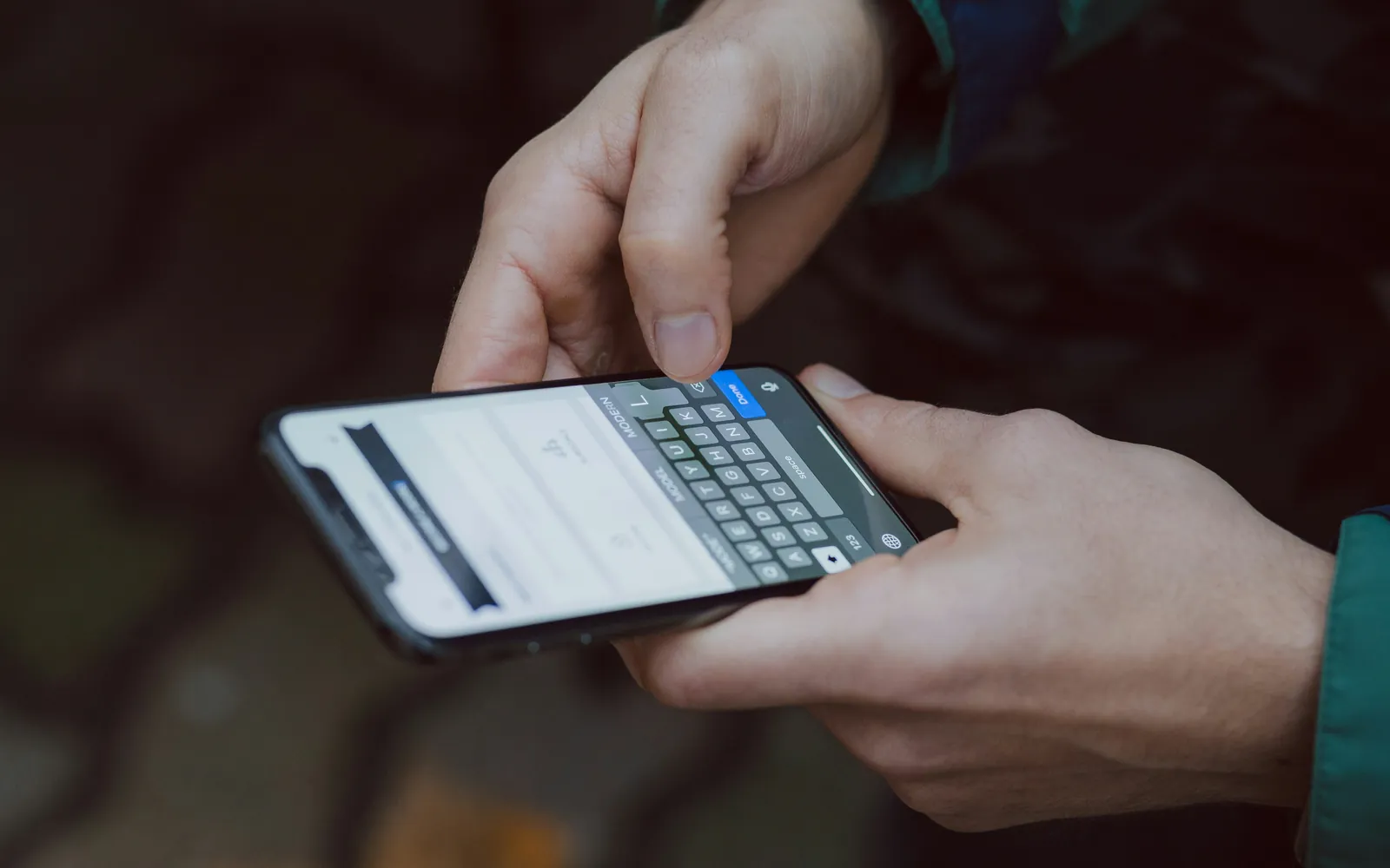 Mãos digitando em um celular, em ambiente escuro